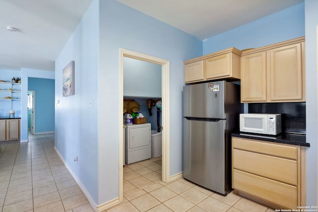 kitchen with washer and clothes dryer, stainless steel fridge, light tile patterned flooring, and light brown cabinets