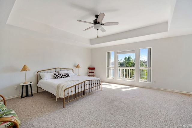 carpeted bedroom with a tray ceiling and ceiling fan