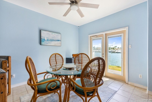 dining area with ceiling fan, a water view, and light tile patterned floors