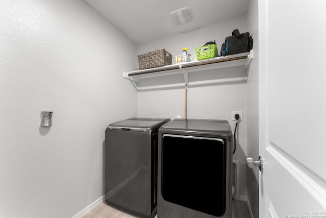 clothes washing area featuring separate washer and dryer and light hardwood / wood-style floors