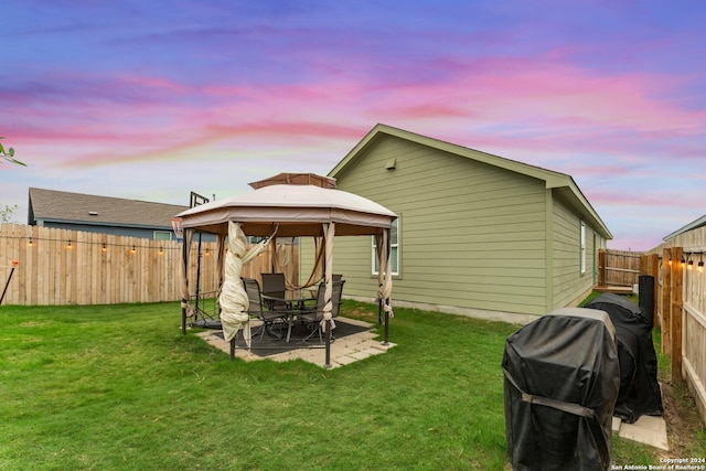 back house at dusk with a gazebo, a yard, and a patio