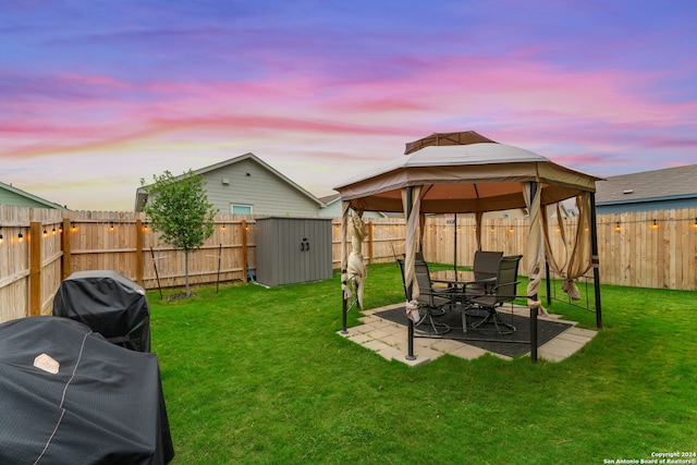 yard at dusk with a gazebo, a patio, and a shed