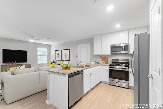 kitchen featuring ceiling fan, sink, stainless steel appliances, light hardwood / wood-style flooring, and white cabinets