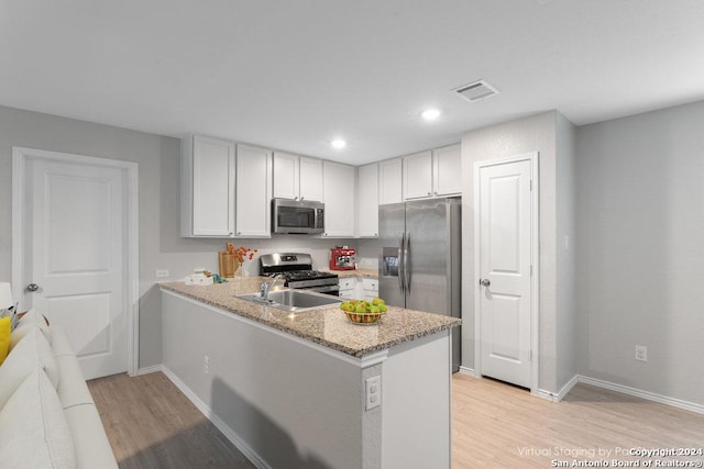 kitchen featuring kitchen peninsula, white cabinetry, light wood-type flooring, and appliances with stainless steel finishes