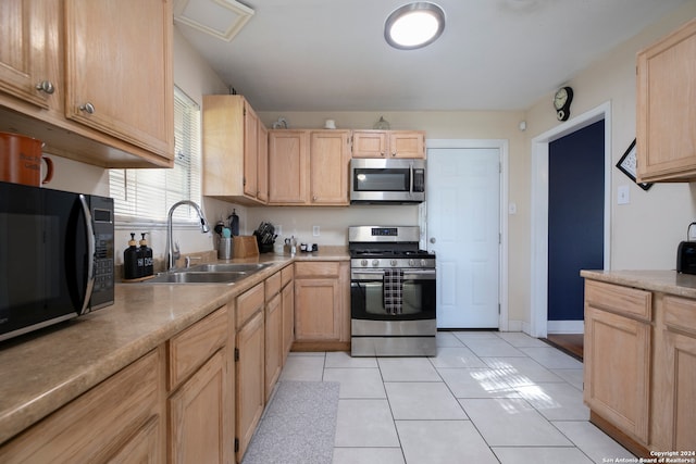 kitchen with light brown cabinets, stainless steel appliances, light tile patterned floors, and sink