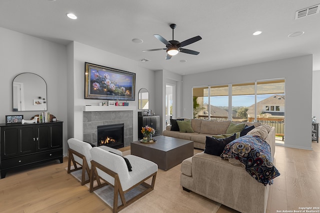 living room with ceiling fan, a fireplace, and light wood-type flooring