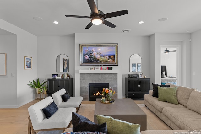 living room with ceiling fan, light hardwood / wood-style floors, and a tile fireplace