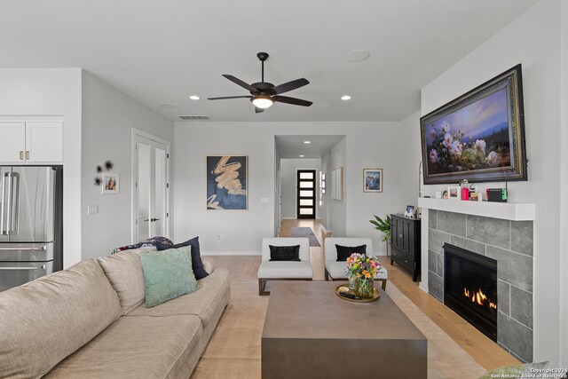 living room featuring ceiling fan, a fireplace, and light hardwood / wood-style floors