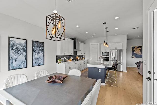 dining area with sink, light hardwood / wood-style flooring, and an inviting chandelier