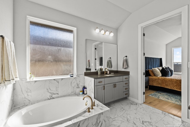 bathroom with a wealth of natural light, a relaxing tiled tub, and lofted ceiling