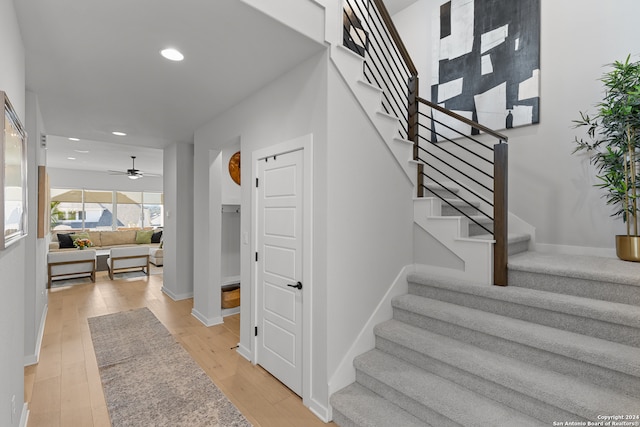 stairs featuring ceiling fan and hardwood / wood-style flooring