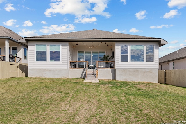 rear view of property featuring a yard and ceiling fan