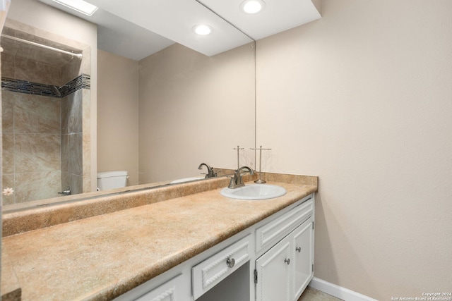 bathroom with tiled shower, vanity, and toilet