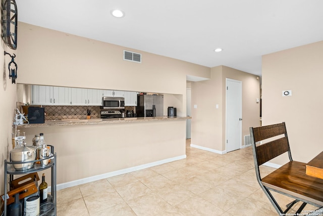 kitchen with white cabinetry, stainless steel appliances, tasteful backsplash, kitchen peninsula, and light tile patterned floors