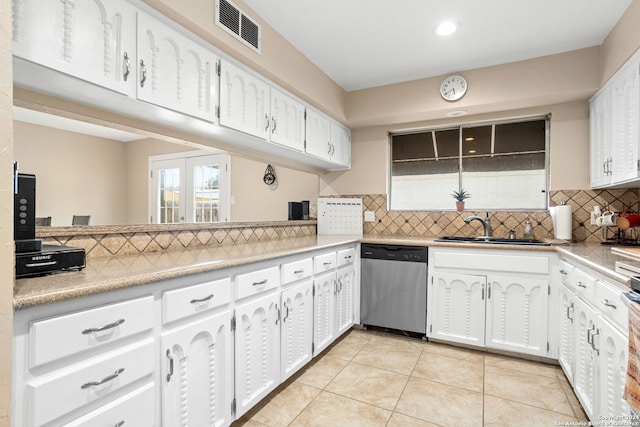 kitchen with dishwasher, white cabinets, sink, light tile patterned floors, and tasteful backsplash