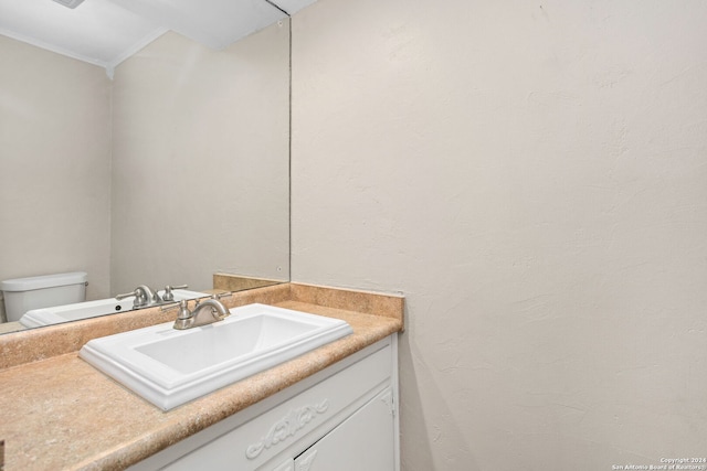 bathroom featuring vanity, toilet, and ornamental molding