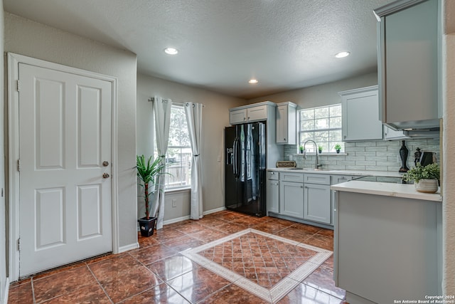 kitchen featuring gray cabinets, black fridge with ice dispenser, a healthy amount of sunlight, and sink