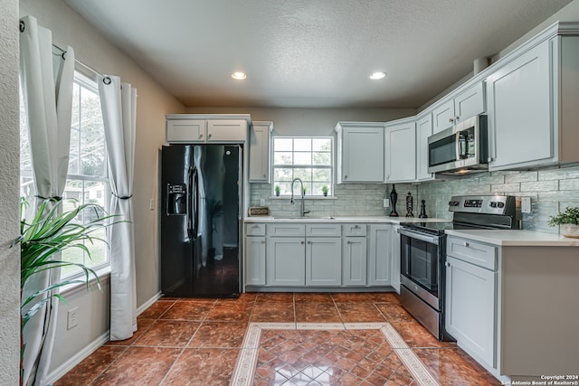 kitchen featuring decorative backsplash, stainless steel appliances, plenty of natural light, and sink