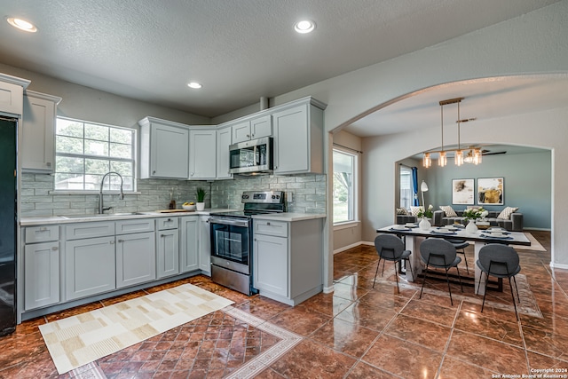 kitchen featuring pendant lighting, a textured ceiling, stainless steel appliances, and sink