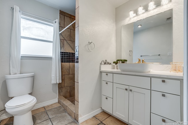 bathroom with tile patterned floors, vanity, a tile shower, and toilet