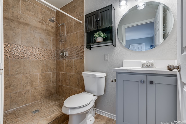 bathroom featuring a tile shower, vanity, and toilet