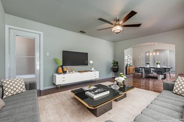 living room featuring dark tile patterned flooring and ceiling fan with notable chandelier