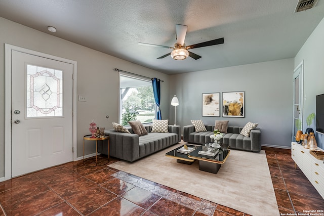 living room with ceiling fan and a textured ceiling