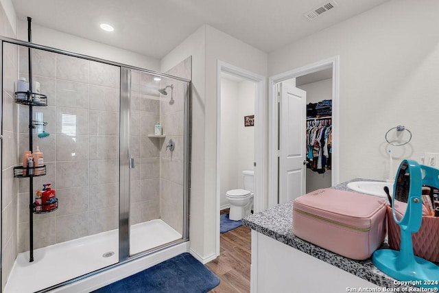 bathroom with toilet, vanity, a shower with shower door, and hardwood / wood-style flooring