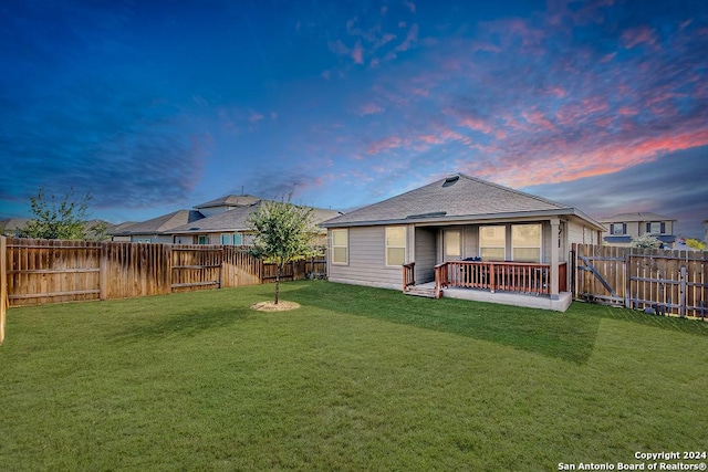 back house at dusk featuring a yard and a patio