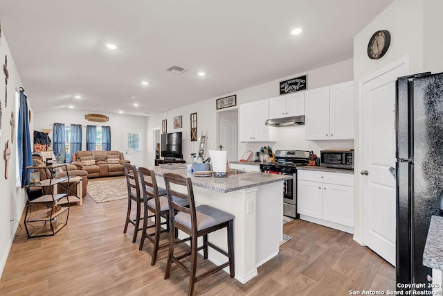 kitchen with white cabinetry, light stone countertops, stainless steel appliances, light hardwood / wood-style flooring, and a kitchen island