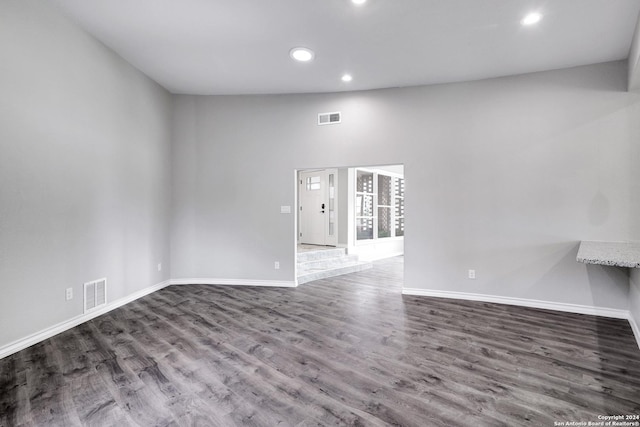 empty room with wood-type flooring and high vaulted ceiling