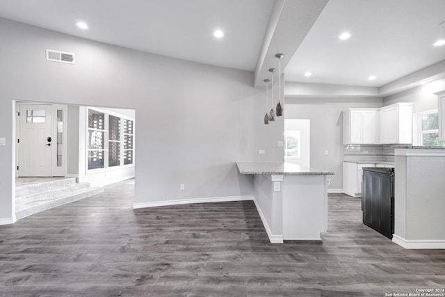 kitchen with dark hardwood / wood-style floors, light stone counters, white cabinetry, and kitchen peninsula