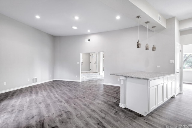 kitchen with decorative light fixtures, white cabinetry, dark wood-type flooring, and light stone counters