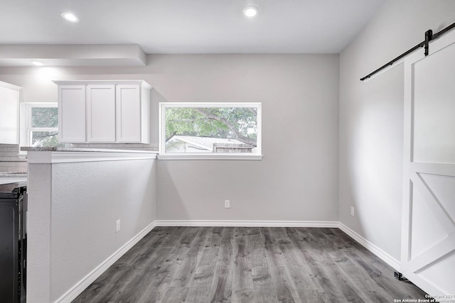 unfurnished dining area with a barn door and light hardwood / wood-style floors