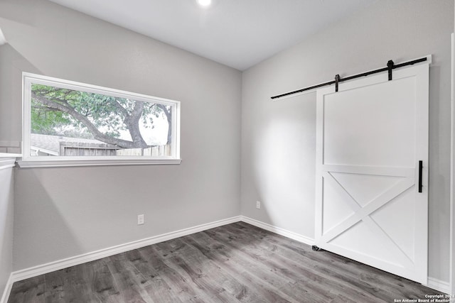 unfurnished bedroom featuring a barn door and dark wood-type flooring