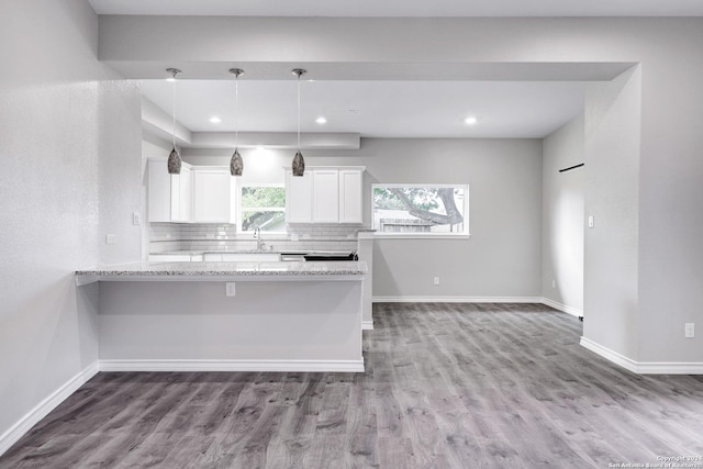 kitchen with backsplash, light stone counters, pendant lighting, light hardwood / wood-style flooring, and white cabinets