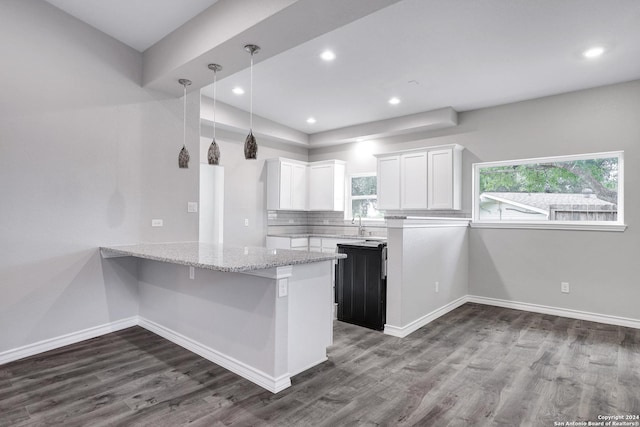 kitchen with hardwood / wood-style floors, hanging light fixtures, light stone countertops, white cabinetry, and kitchen peninsula