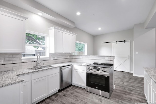 kitchen featuring appliances with stainless steel finishes, sink, a barn door, dark hardwood / wood-style floors, and white cabinetry