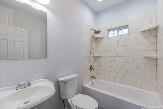 full bathroom featuring tiled shower / bath combo, toilet, and sink