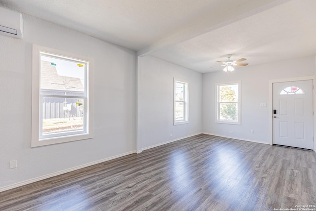 interior space featuring an AC wall unit, ceiling fan, wood-type flooring, and a textured ceiling