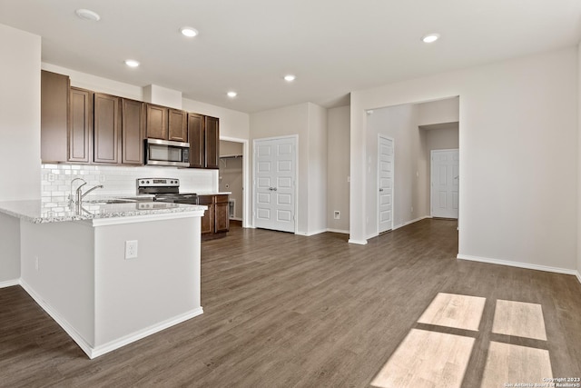 kitchen with dark hardwood / wood-style floors, light stone counters, sink, and appliances with stainless steel finishes