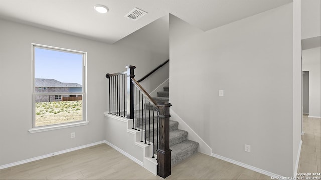 stairs with plenty of natural light and wood-type flooring