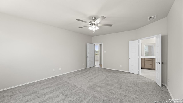 unfurnished bedroom with connected bathroom, ceiling fan, and light carpet