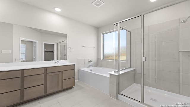 bathroom featuring plus walk in shower, vanity, and tile patterned floors