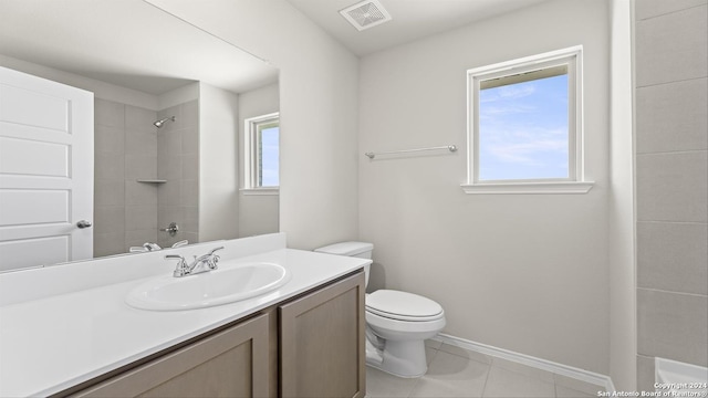 bathroom featuring tile patterned floors, vanity, a tile shower, and toilet