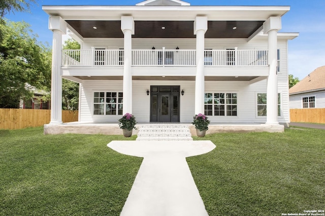 view of front of house featuring french doors, a balcony, and a front yard