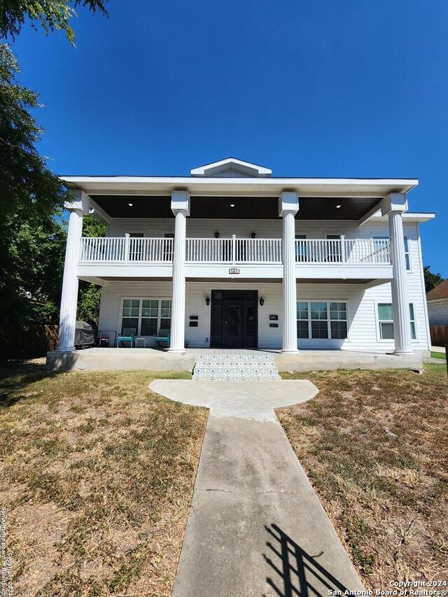 view of front facade featuring a balcony and a front lawn