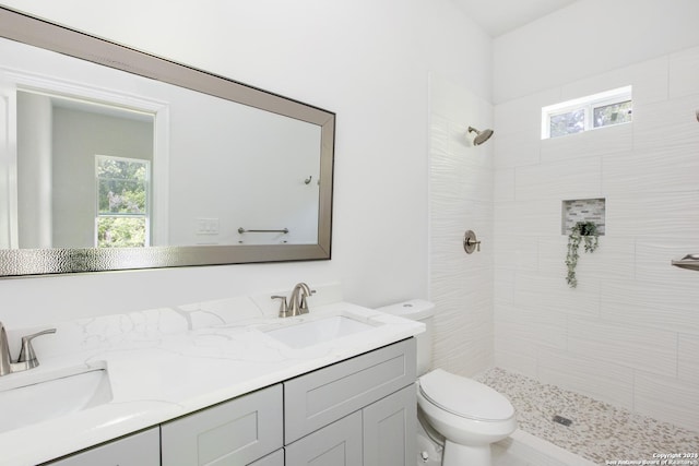 bathroom featuring a tile shower, vanity, and toilet