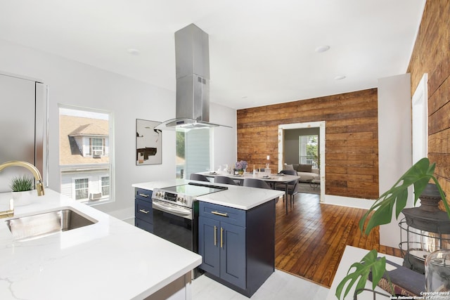 kitchen featuring sink, wooden walls, electric range, light wood-type flooring, and island range hood