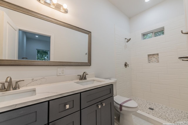 bathroom featuring a tile shower, vanity, and toilet